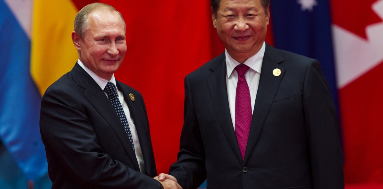 A picture of Xi Jinping and Vladimir Putin shaking hands.