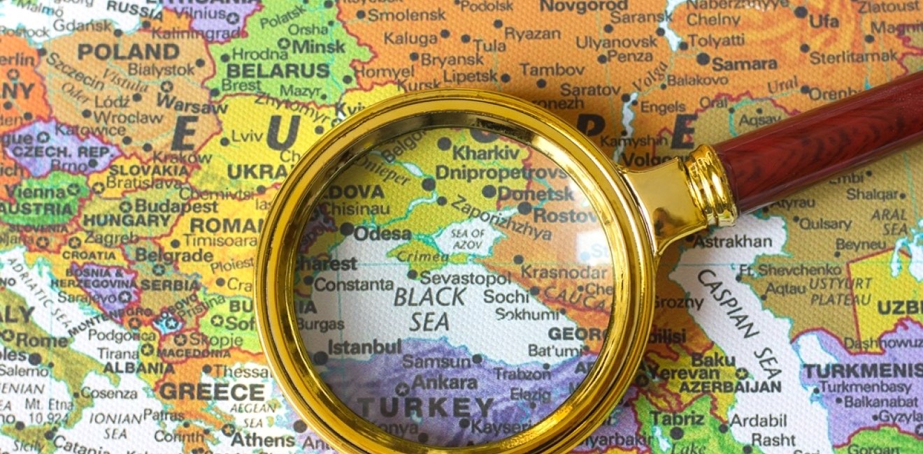 A looking glass centered over a map of the Black Sea.