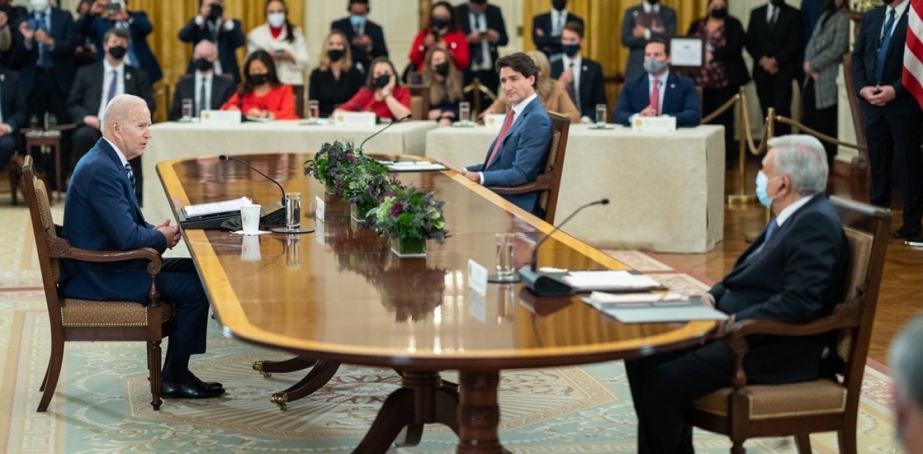 President Biden, President Lopez Obrador, and Prime Minister Trudeau sit at a table and talk