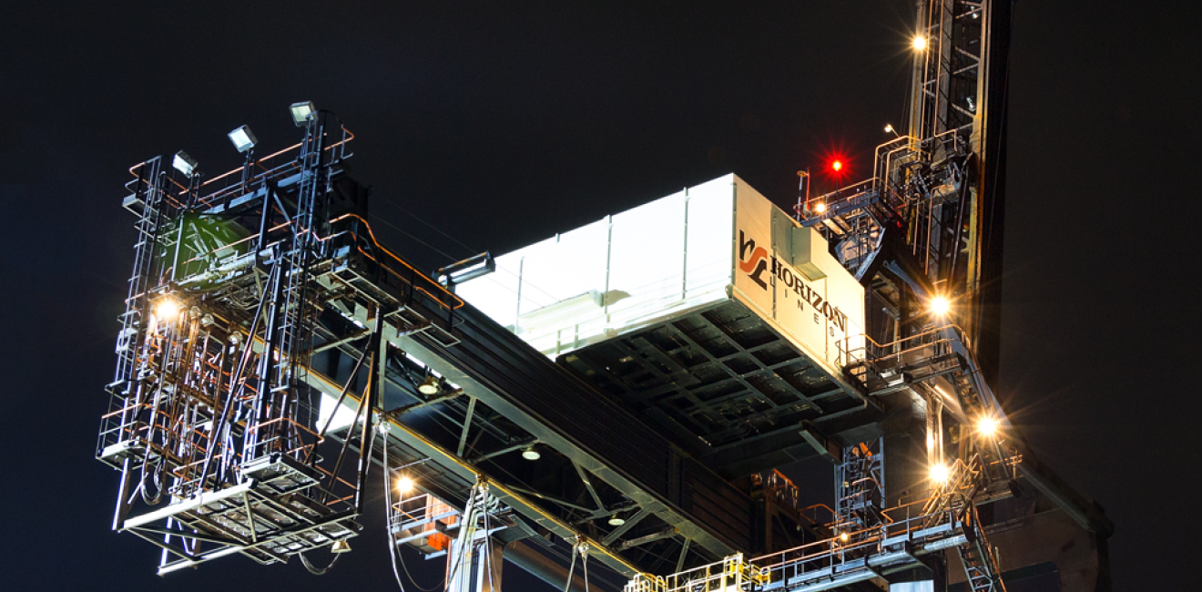 Dutch Harbor, Unalaska, Alaska, USA - August 14th, 2017: Night view of a port crane for shipping containers operated by Horizon Lines located at the port of Unalaska, Alaska