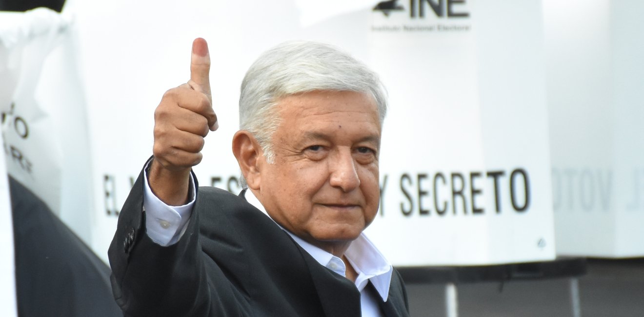 AMLO gives a thumbs up with his ink-stained finger.