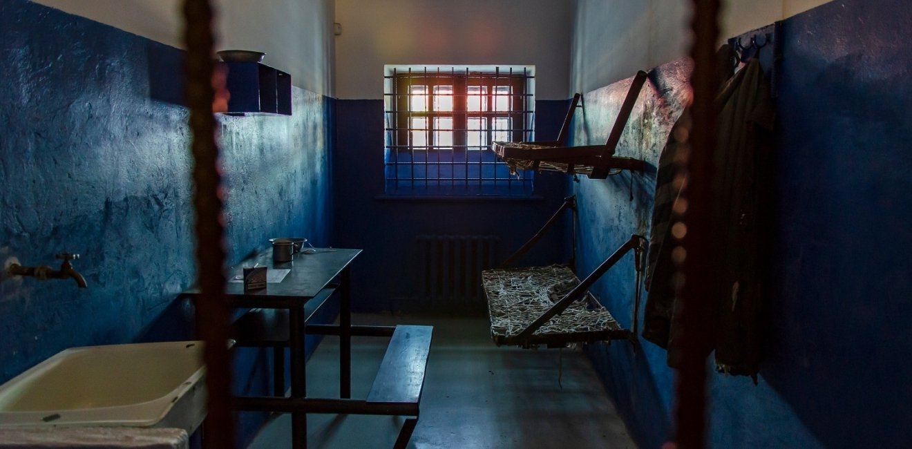 Empty prison cell in Russia. Two beds, a table, a washstand and a toilet are behind bars.