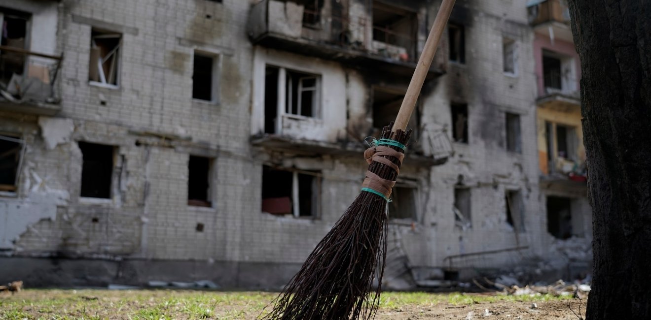 Broom in foreground, bombed building in background