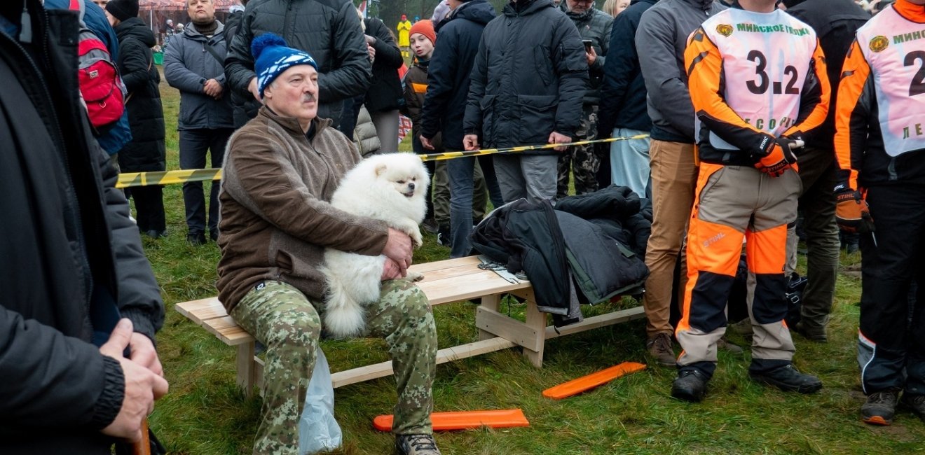 President Lukashenko sitting with a small white dog among a crowd of people 