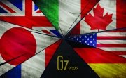 A picture of the seven flags of the G7 countries on fracturing glass shards.