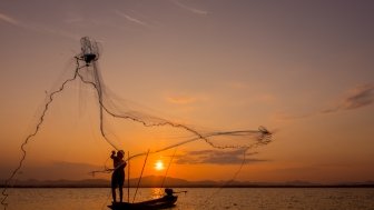 Silhouette of fisherman throwing net on the lake, Shutterstock