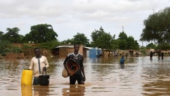 In the Kirkissoye neighborhood in Niamey, people carry their belongings while walking in a street flooded by waters from the Niger river. 