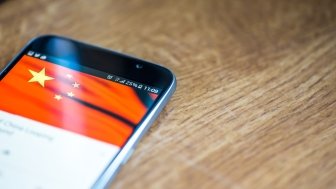 smartphone with Chinese flag on a wooden background 