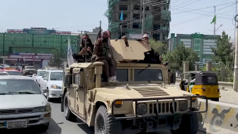 Taliban fighters riding a tank in the streets of Kabul.