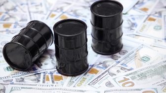 A picture of three oil barrels on a stack of U.S. currency