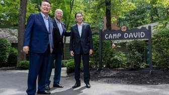 Presidents Yoon and Biden stand with Prime Minister Kishida in front of the sign for Camp David.