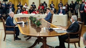 President Biden, President Lopez Obrador, and Prime Minister Trudeau sit at a table and talk