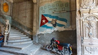 The image shows a painting of Fidel Castro on a worn-down wall in Old Havana