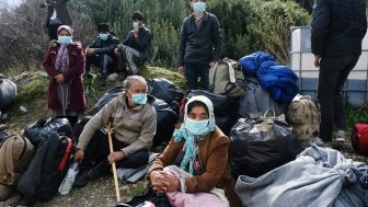 Refugees with masks awaiting transport in Greece