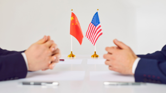 Flags of America and China stand on table during talks between diplomats