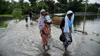 People wade through flooded road at flood effected Kalgachi in Barpeta