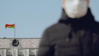 Man with mask in front of Belarus flag