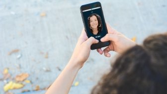 Woman unlocking smartphone with facial recognition technology. Biometric verification and face recognition concept.