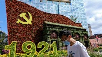 Beijing China - July 3 2021: A man walks in front of a display marking the centennial anniversary of the Communist Party of China (CPC) 