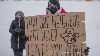 Protester in snow with sign that reads "That one neighbor that never leaves you alone" and a caricature representing the Russian state