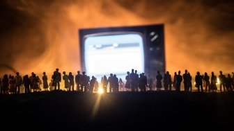 Gathering of people surrounding a large screen