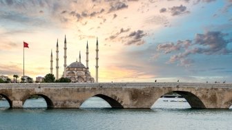 Sabanci Central Mosque and Stone bridge in Adana, Turkey, and the view of Seyhan river with sunset sky. Landmarks in the city of Adana, Turkey