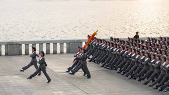 Squad of female teenagers in military uniforms rehearses for a parade