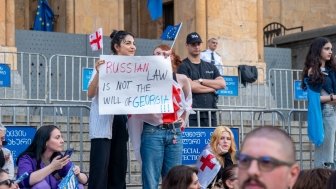 Protesters at Georgian parliament building in Tbilisi with flags and placards