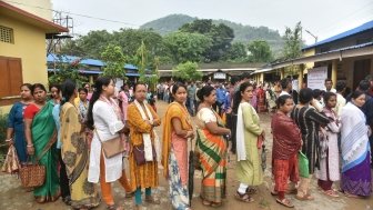 A group of people wait in line to cast their votes.