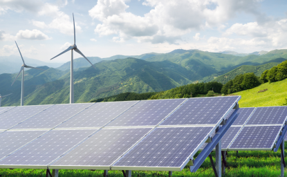 Solar panels and wind turbines against mountain landscape.