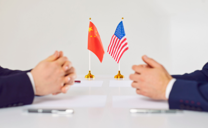 Flags of America and China stand on table during talks between diplomats