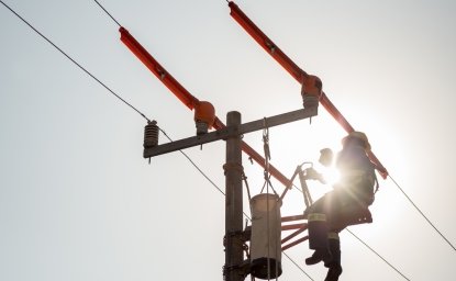 Lineman electrician engineer working climbing a pole to repair and maintain a power line and a transformer