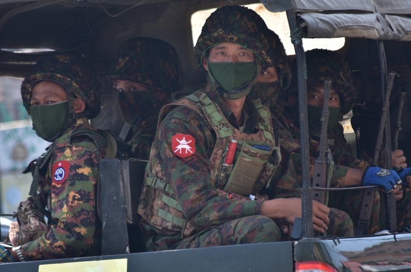 Soldiers in uniforms and masks sitting on a truck.