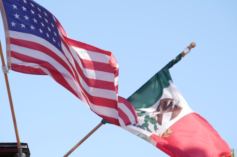 Mexican tricolor and American flag waving on wind.