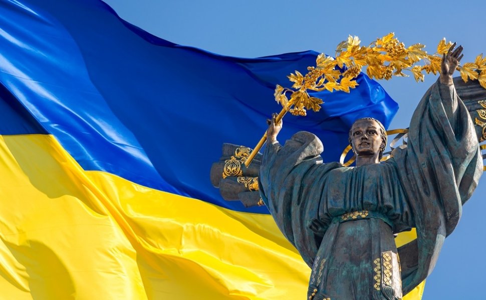 Monument of Independence of Ukraine in front of the Ukrainian flag. The monument is located in the center of Kyiv on Independence Square.