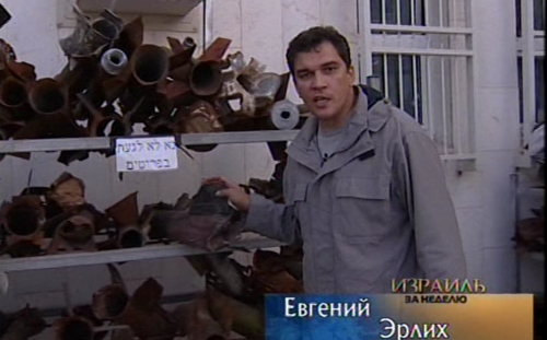 Newscaster next to spent artillery shells