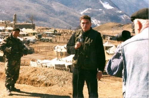 Man holding mic outside of a camp