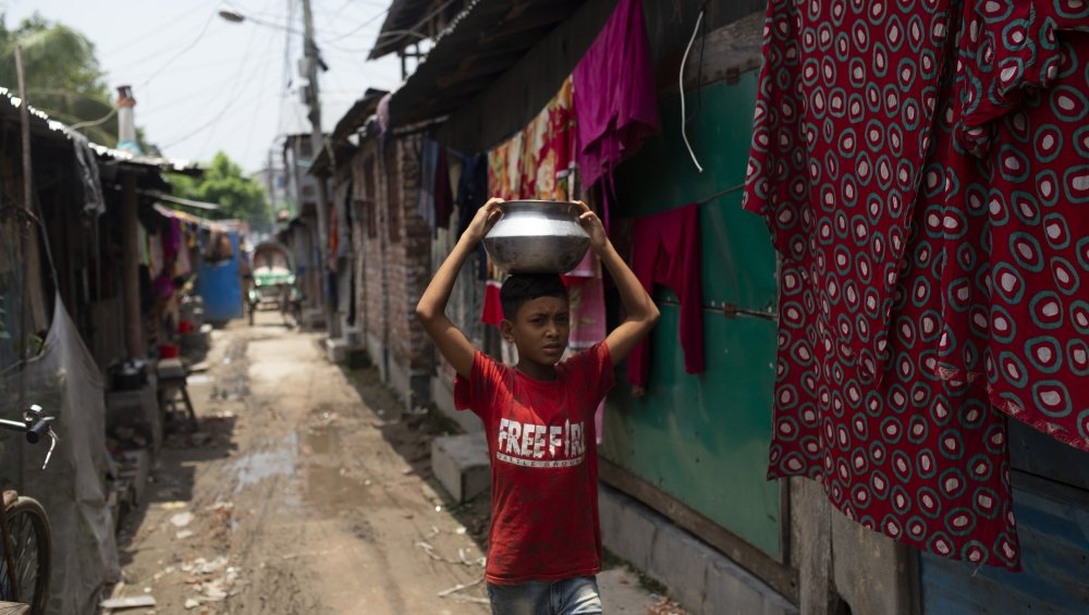 A young boy collects drinking water in his Barisal slum